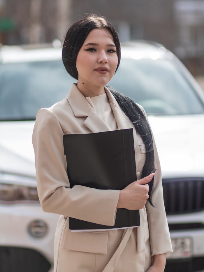 Services Asian businesswoman holding a black folder, exuding confidence in a professional setting.