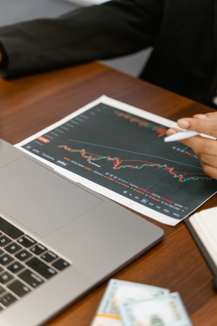 Close-up of business analysis with a laptop, chart, and currency on a wooden table.